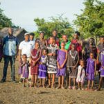 A diverse group of Tanzanian people in traditional attire outdoors, showcasing cultural heritage.